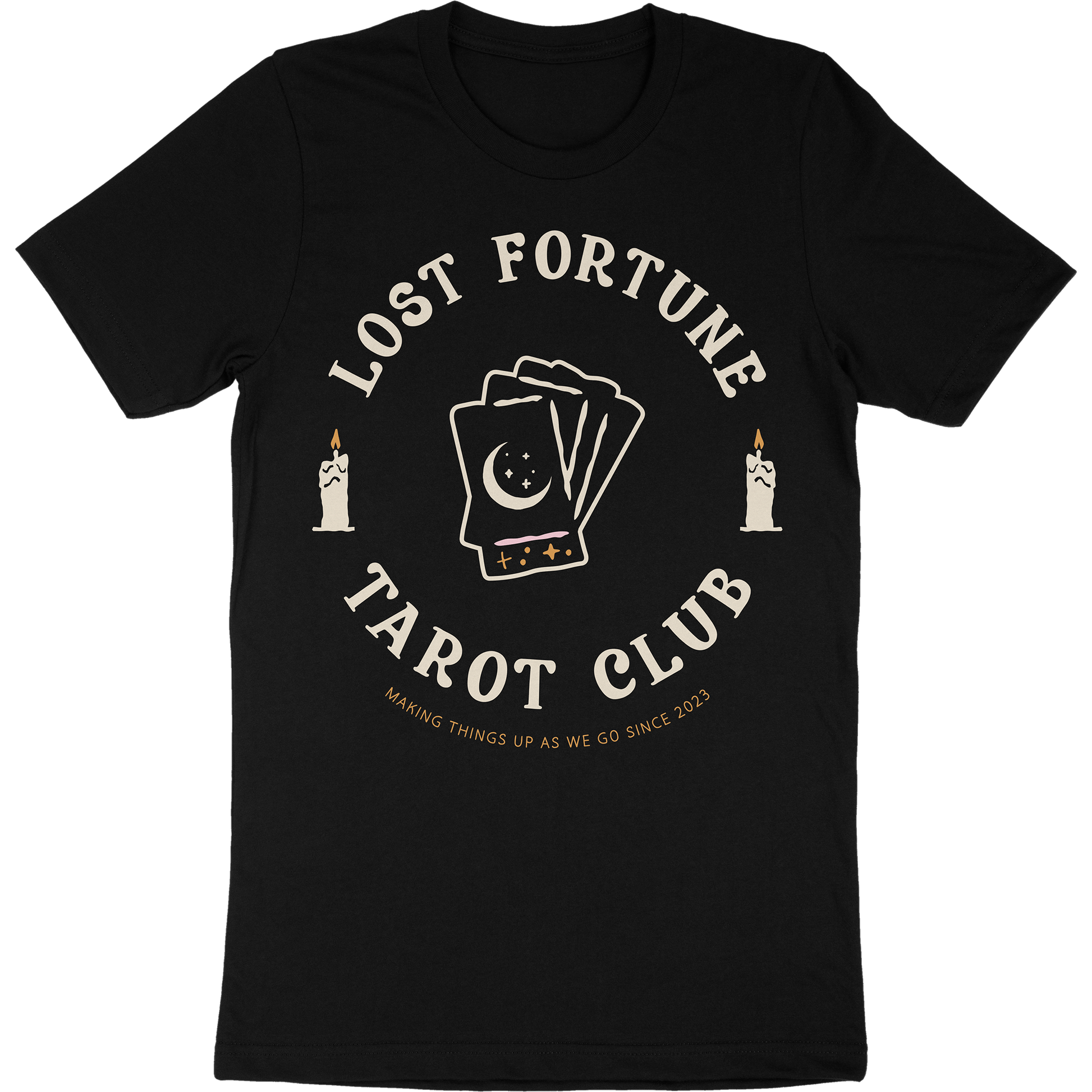 Black t-shirt with artwork of candles and a stack of tarot cards with a moon and stars on the front. The text reads "Lost Fortune Tarot Club. Making things up as we go since 2023." 