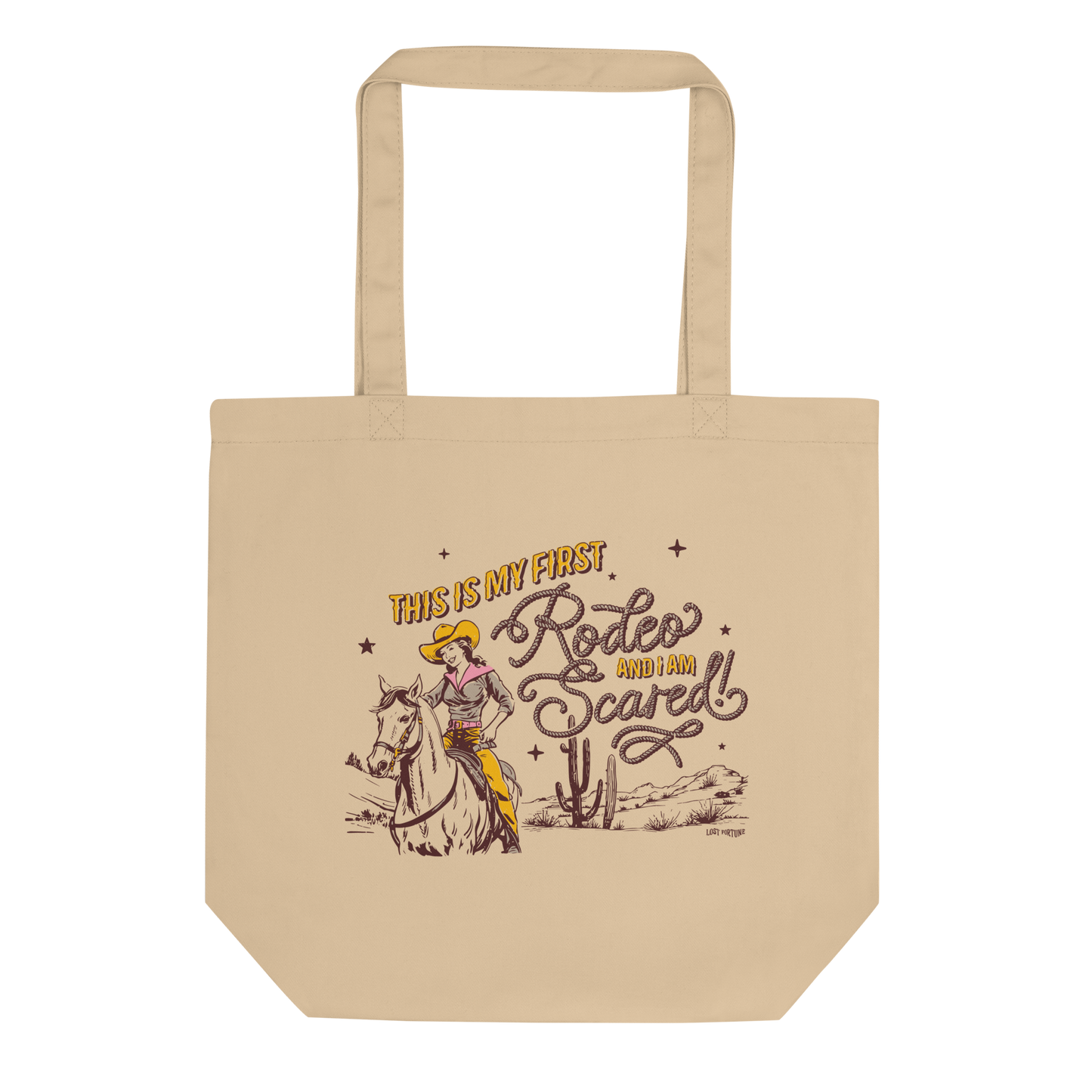 Tan tote bag that features artwork of a cowgirl riding a horse in the desert and the phrase "this is my first rodeo and I am scared"