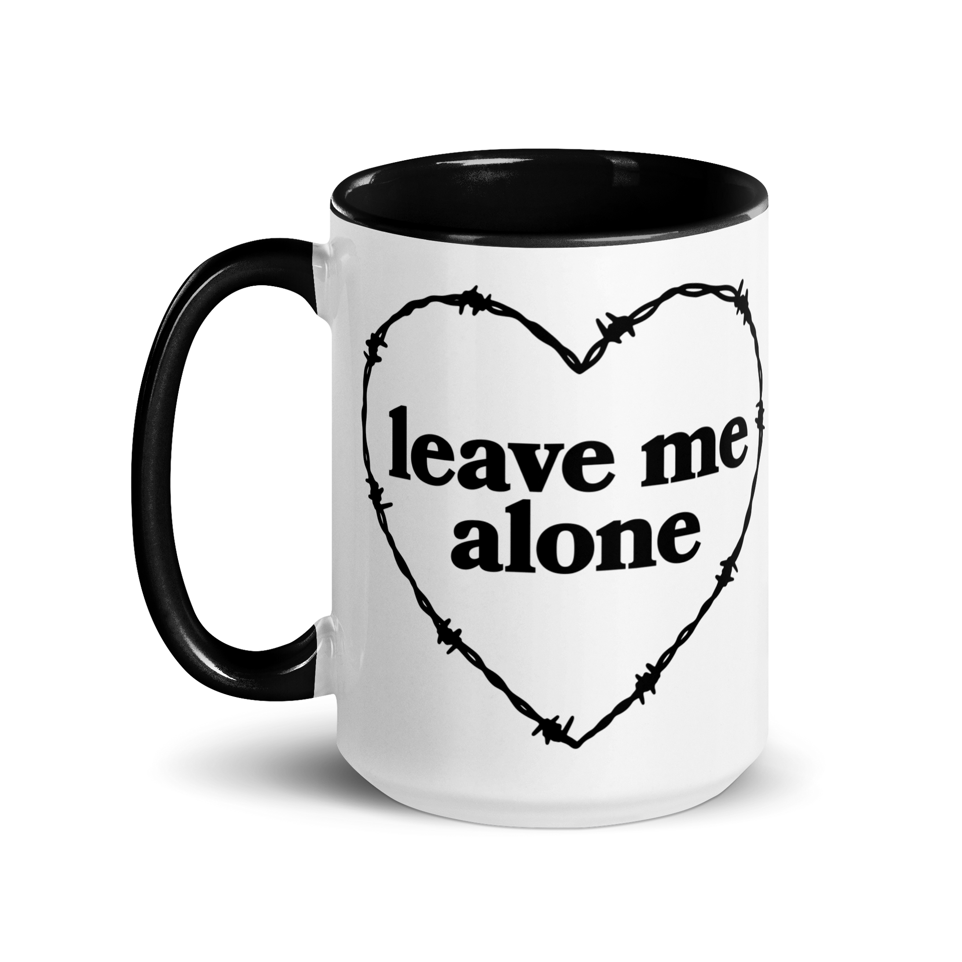 White ceramic mug with black handle and interior that features a barbed wire heart surrounding the phrase "leave me alone"